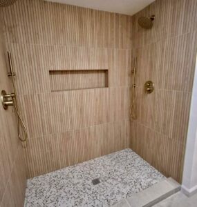 Before and after tub-to-shower conversion in Strongsville featuring herringbone porcelain tile and a curbless entry.