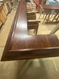 Handcrafted solid Cherry wood bar top with a deep Espresso finish and a traditional Ogee edge profile. The Ultimate Speakeasy Vibe. There is nothing quite like the deep, soul-warming glow of solid Cherry. We treated this handcrafted bar top with a custom Espresso stain to bring out the wood's regal character, making it the undisputed centerpiece of this basement entertainment suite.