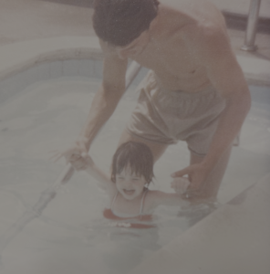 Shannon at age 2 with her dad, Brandt in the pool. He is clutching her arms and holding her above the water. | Mr.Countertops