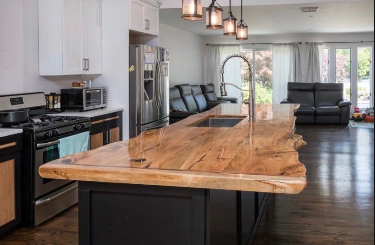 Custom live edge black walnut kitchen island top with natural wood grain and satin finish in a luxury home.