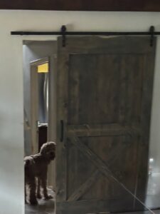 Solid reclaimed timber barn door with a handcrafted herringbone pattern and traditional iron hardware in a rustic farmhouse pantry.