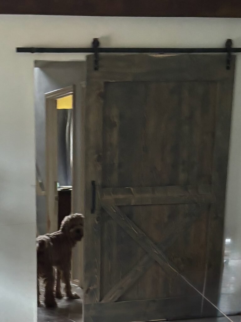 Solid Oak Barn Door with beloved Goldendoodle standing behind it, the door was Built by Mr.Countertops in Wadsworth, OH