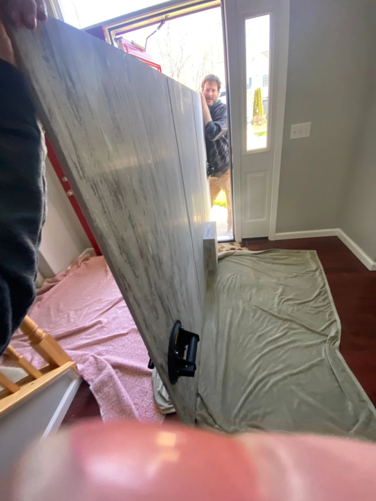 The team at Mr.Countertops, Shannon and David stop at the bottom of the stairs before carrying custom 250 pound shower panel for a bathroom renovation in Copley Ohio.