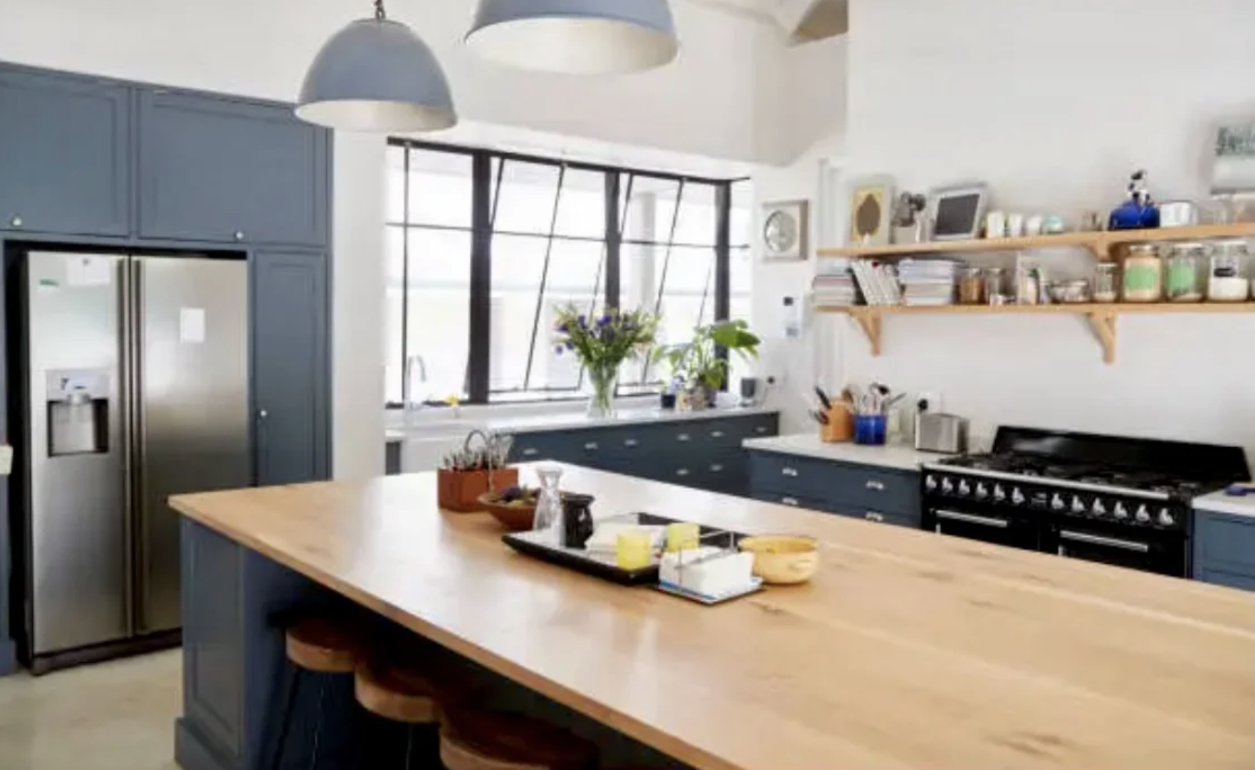 Large solid white oak kitchen island in a modern industrial farmhouse remodel with navy blue cabinets and black pendant lighting.