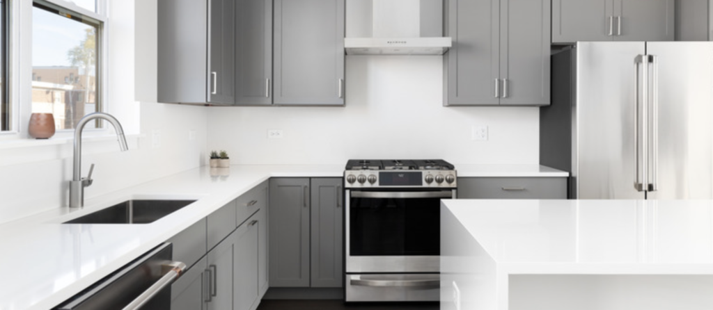 Complete kitchen remodel in Brunswick, Ohio, featuring warm slate gray cabinetry, custom white solid surface countertops with an integrated sink, and modern brushed nickel hardware.