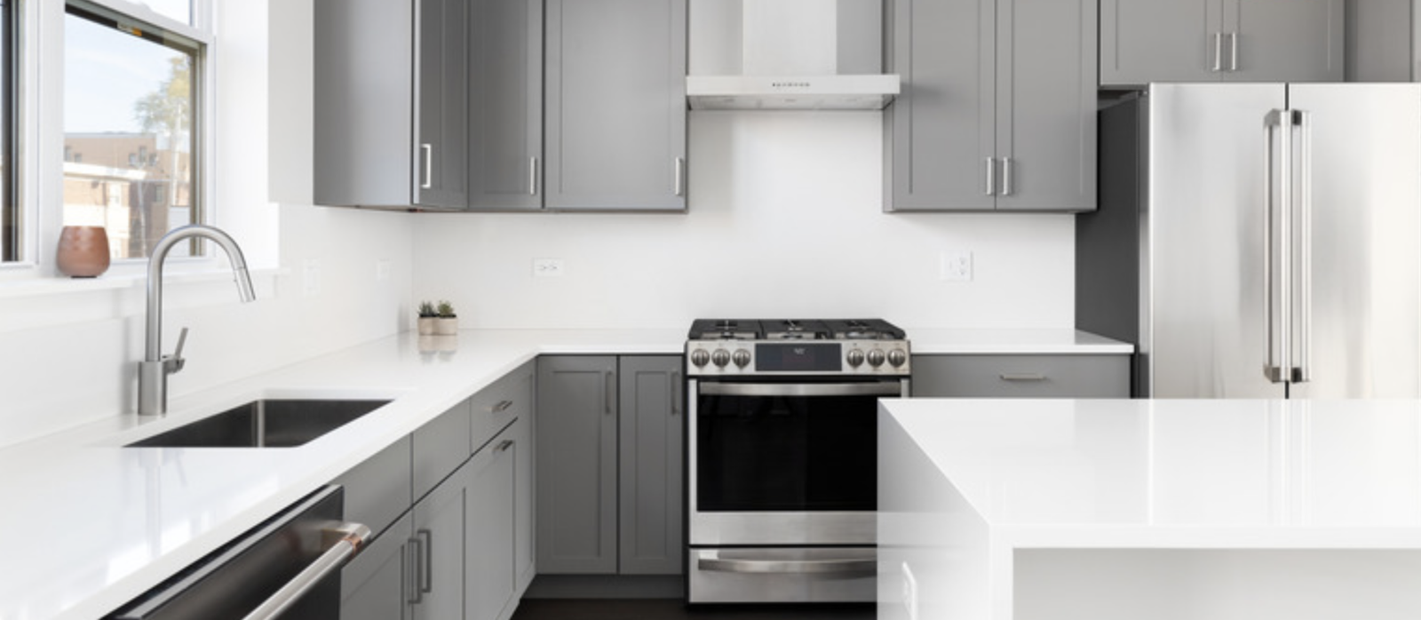 Complete kitchen remodel in Brunswick, Ohio, featuring warm slate gray cabinetry, custom white solid surface countertops with an integrated sink, and modern brushed nickel hardware.