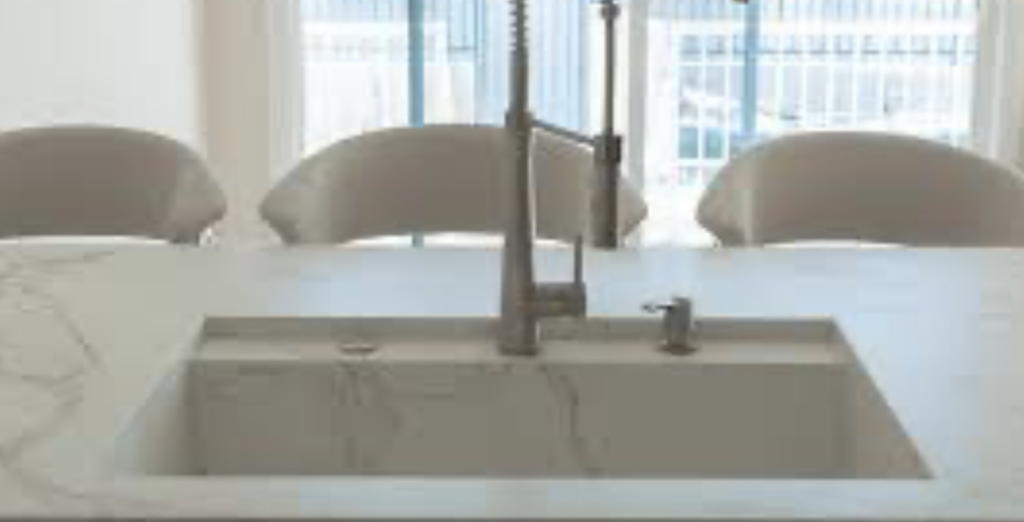Gray and tan veined engineered stone hotel island with an integrated sink for a commercial Cleveland hospitality project