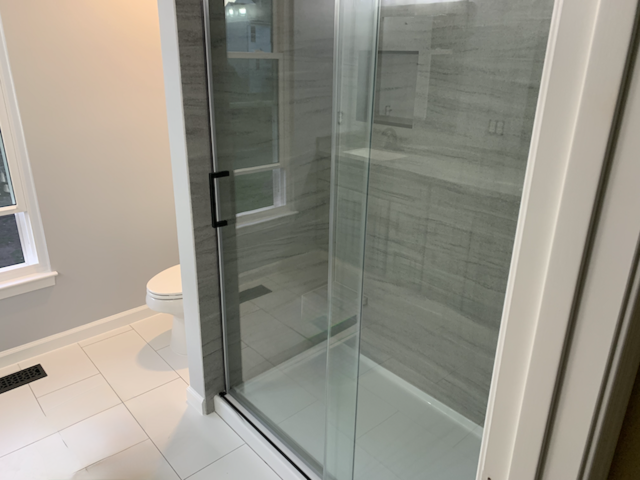 Completely transformed bathroom with tub-to-shower conversion, custom shower panels, tile flooring and glass enclosure